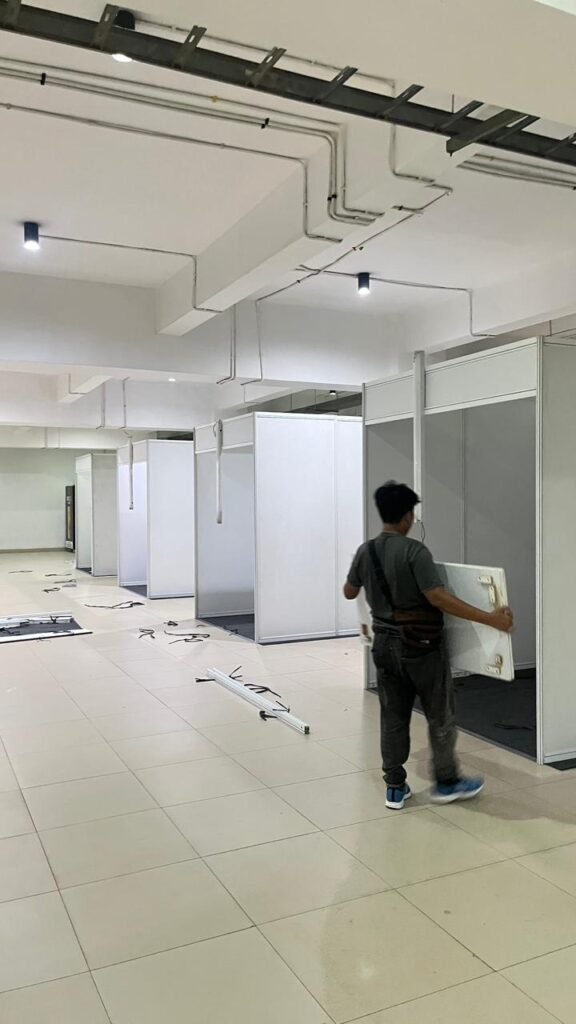 Tim Zein Event Production memasang partisi booth pameran dengan rapi.